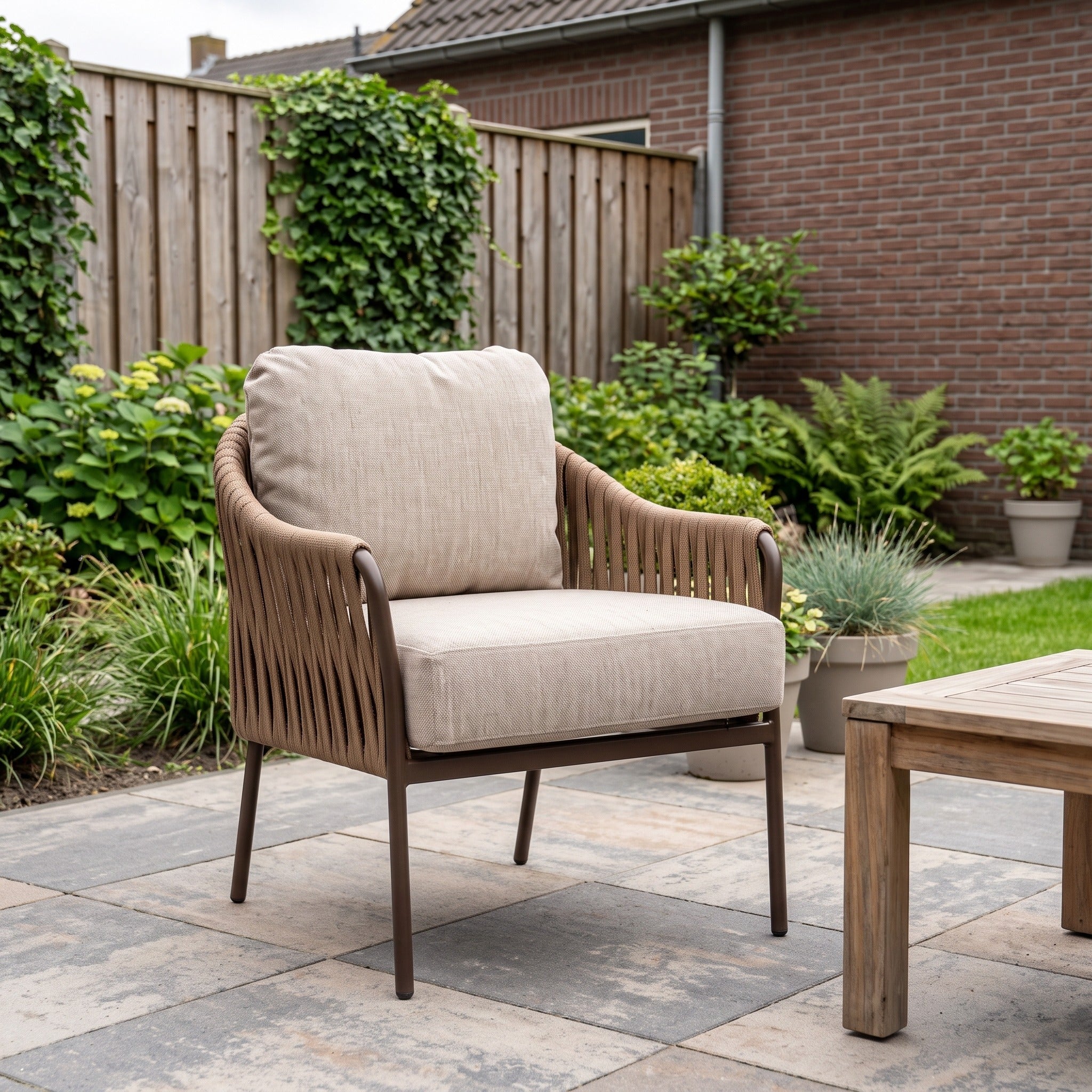 Yoi Hydra low dining stoel alu bronze/belt toffee/flax beige AW in een Nederlandse tuinomgeving