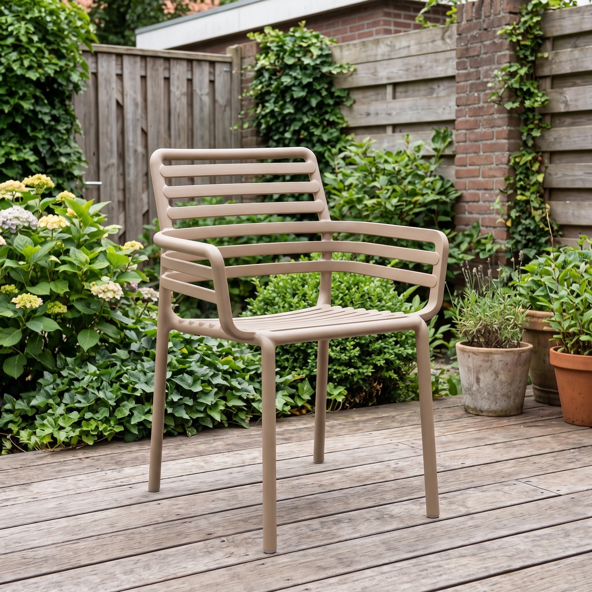 Nardi Doga Armstoel cappuccino in een Nederlandse tuinomgeving