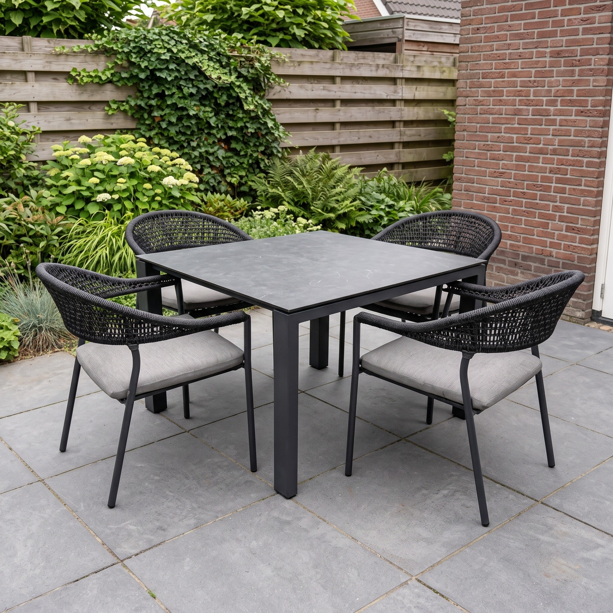 4 Seasons Outdoor 4-delige diningset 4x Sienna dining stoel antraciet 1x Goa tafel HPL 95x95 in een Nederlandse tuinomgeving